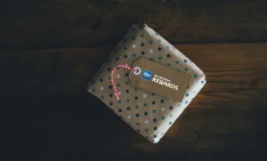 Nell'immagine un pacchetto regalo messo su un tavolo di legno. Sul pacchetto la targhetta Best Western Rewards®.