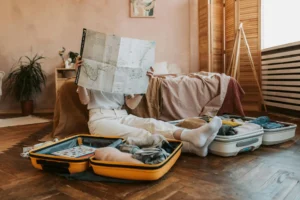 Nell'immagine una ragazza che prepara la valigia per partire.